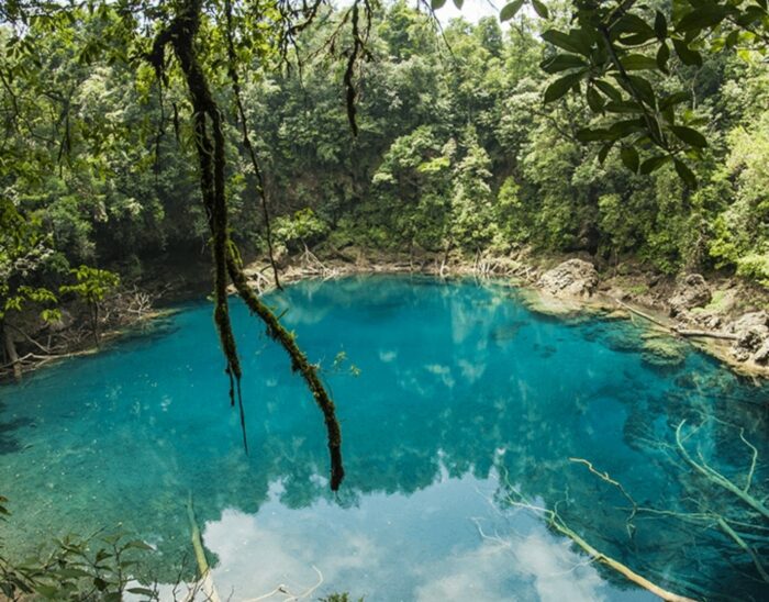 Vue d'un lac bleu entouré de végétation luxuriante dans la région de Huehuetenango, Guatemala, célèbre pour ses paysages naturels.