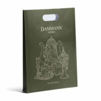 Un sac cadeau vert foncé avec des illustrations dorées de théières, une tasse et d'autres objets de thé, et le logo "DAMMANN FRÈRES" au centre. Le design est élégant, rappelant l'art de servir le thé avec raffinement.